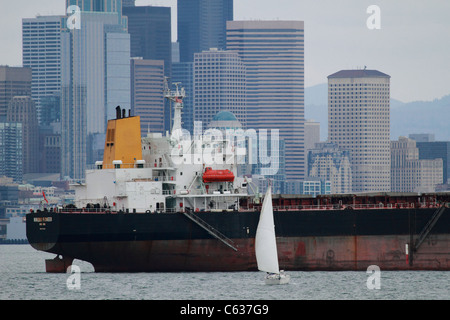 Pesante nave di stazza Ningbo Pioneer da Hong Kong ancorato in Elliot Bay di fronte a Seattle, Washington con una barca a vela rivolta Foto Stock