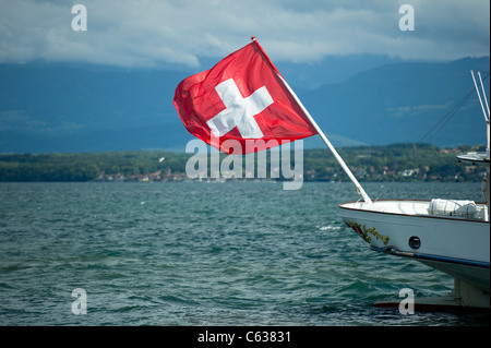 Bandiera svizzera battenti nel vento in corrispondenza della parte posteriore della barca di piacere su Lac Leman, Nyon, Svizzera. Foto Stock