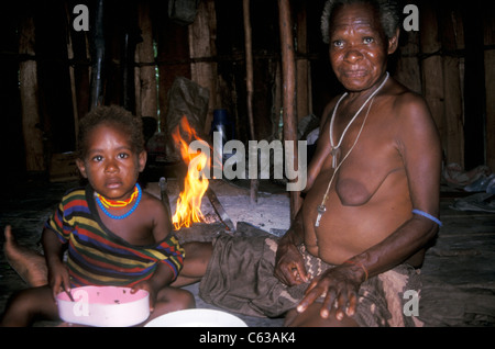 Nel villaggio di reinsediamento di Kwamki lama, fuori Timika, un esteso gruppo familiare di Dani degli altopiani vive nelle loro tradizionali capanne di paglia a forma di alveare. Papua Occidentale, Indonesia Foto Stock