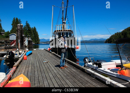 L'uomo texting che è arrivato alla sua destinazione da un dock in Bamfield BC Foto Stock