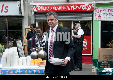 Clarence Road Hackney. Street tea party una settimana dopo i tumulti.Marchi e Spencers manager con teiere e piastre Foto Stock