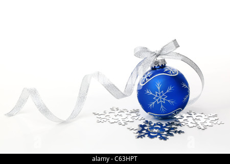 Blue palla di Natale con nastro argentato di prua e il simbolo del fiocco di neve su sfondo bianco. Foto Stock