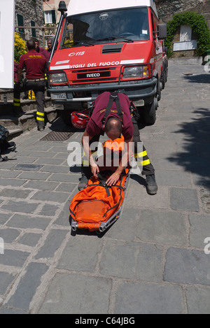 Un elemento maschio dei Vigili del Fuoco, una nazionale italiana di vigilanza antincendio corps prepara una barella su una strada di Vernazza, Italia. Foto Stock