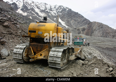 Bulldozer cancella percorso attraverso una frana come convoglio di camion attendere nelle vicinanze sul treacherous strada himalayana di Leh Ladakh Foto Stock