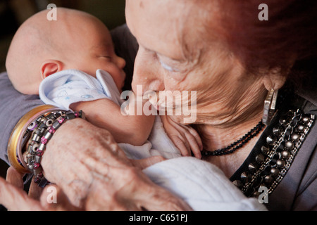 Una vecchia donna (bisnonna) azienda e baciando un neonato. Foto Stock