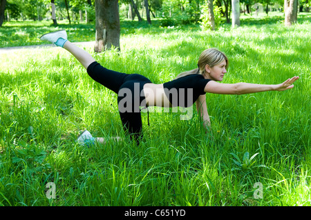 Bella ragazza è impegnata nella ginnastica all'erba verde Foto Stock