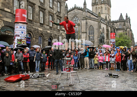 Edimburgo Scozia trafficato centro cittadino Fringe Festival di bilanciamento del performer sotto la pioggia sul Royal Mile nel centro della città Foto Stock