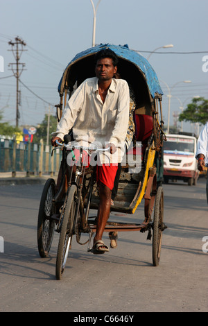 Il triciclo indiano rickshaw trasporta i passeggeri su un'autostrada trafficata in Siliguri Bengala Occidentale India Foto Stock