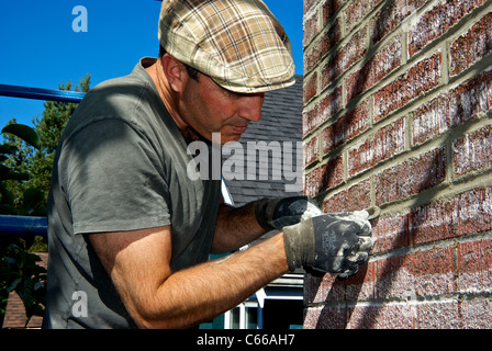 Stone Mason sagomatura di lisciatura della malta cementizia in cotto la riparazione Foto Stock