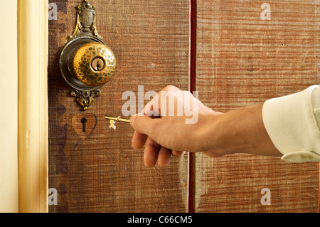 Femmina lato tenendo premuto un tasto per un cuore a forma di toppa di chiave Foto Stock