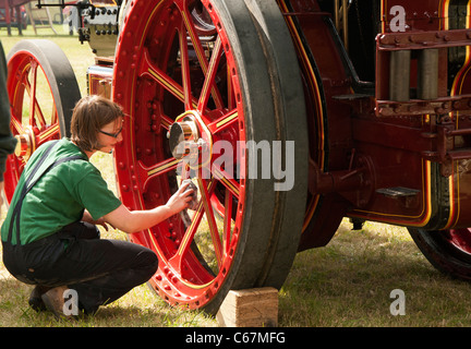 Ragazza la pulizia delle ruote su un vapore motore di trazione al South Cerney Rally a vapore Foto Stock