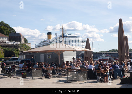 La figura mostra una nave da crociera ormeggiata al porto di Oslo, mentre le persone sedersi fuori nel sole, Norvegia. Foto:Jeff Gilbert Foto Stock