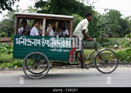 Le ragazze viaggiare a scuola in triciclo rickshaw bus pedale del Bengala occidentale, India Foto Stock