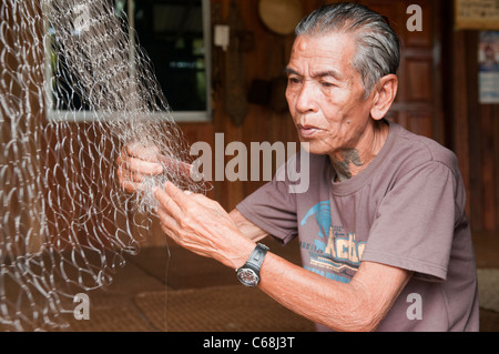 Iban longhouse chief mende sue reti da pesca al Nanga Sumpa longhouse nel Sarawak, Borneo Malaysia Foto Stock