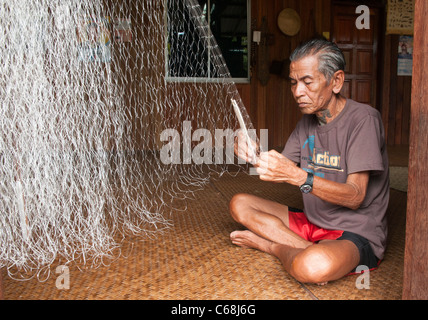 Iban longhouse chief mende sue reti da pesca al Nanga Sumpa longhouse nel Sarawak, Borneo Malaysia Foto Stock