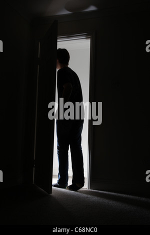 Silhouette di un uomo di lasciare una stanza buia. Foto Stock