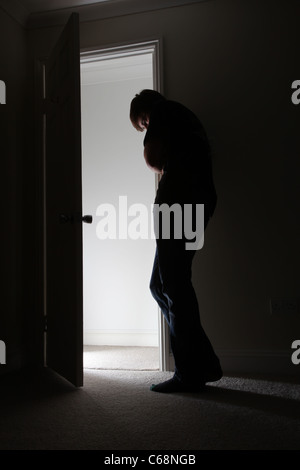 Uomo in piedi da una porta aperta a testa in giù luce proveniente dal corridoio. Foto Stock