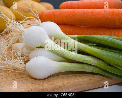 Frühlingszwiebeln, Möhren und Kartoffeln auf einem Schneidbrett | primavera cipolle, carote e patate su un tagliere Foto Stock