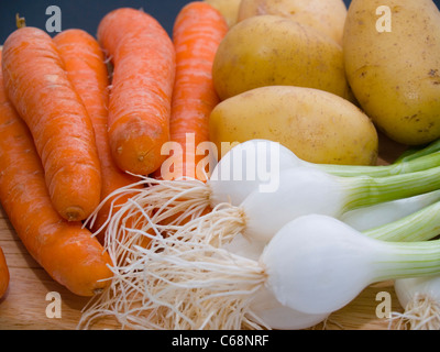 Frühlingszwiebeln, Möhren und Kartoffeln auf einem Schneidbrett | primavera cipolle, carote e patate su un tagliere Foto Stock