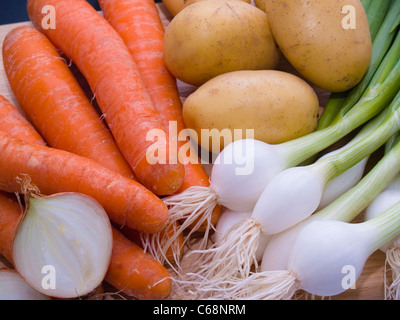 Frühlingszwiebeln, Möhren und Kartoffeln auf einem Schneidbrett | primavera cipolle, carote e patate su un tagliere Foto Stock