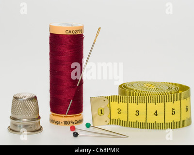 Un filo ritorto roll in questo è un ago di cucitura. Tre spine di fissaggio, una misura di nastro e un ditale sono di fronte a questo Foto Stock