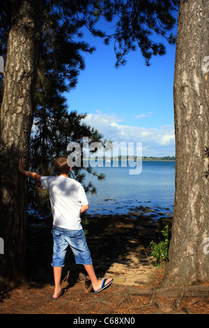 Ragazzo che guarda alla vista del Golfe du Morbihan e Ille aux Moines da Ile de Berder, Larmor-Baden, Morbihan, in Bretagna, Francia Foto Stock