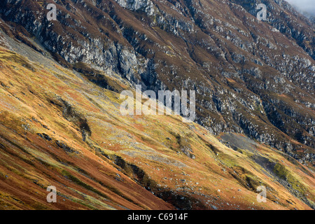 La luce solare che colpisce una montagna di fronte al di sotto del Aonach Eagach Ridge in Glen Coe, Scozia Foto Stock