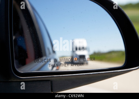 Oggetti in uno specchio sono più vicini di essi appaiono in auto lo specchietto laterale specchietto laterale con carrello in autostrada in Canada Foto Stock