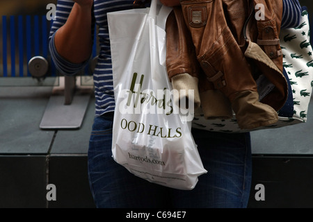 Una plastica Harrods shopping bag essendo portato da un acquirente Foto Stock