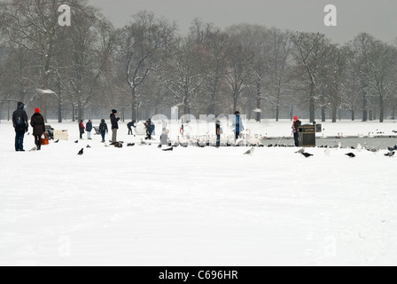 Persone in piedi presso il laghetto rotondo in Hyde Park dopo la nevicata Foto Stock