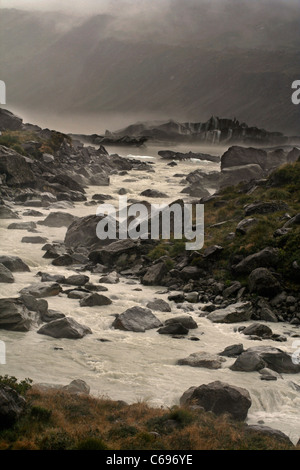 Un fiume formato dalle acque che scorre al di fuori di un lago glaciale, mentre un sedimento incrostati di iceberg galleggianti in background Foto Stock