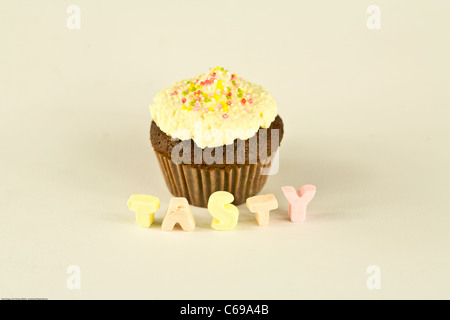 Muffin al cioccolato o tortina isolato su bianco con il cioccolato bianco topping parola gustosa sotto in marsh mellows Foto Stock