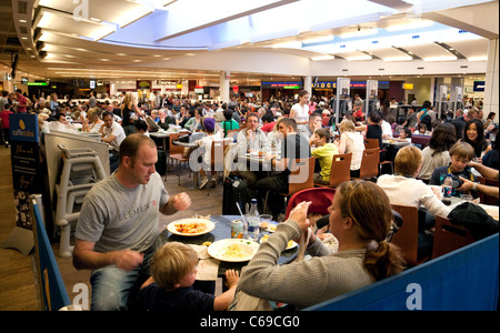 Una folla di persone in attesa nella sala partenze, terminale 3, aeroporto di Heathrow London REGNO UNITO Foto Stock