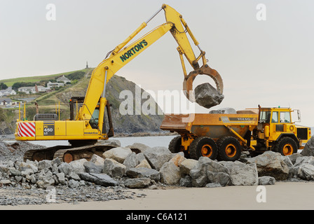 Pietra che viene caricato su un lorrry come parte del mare costruzione di difesa, Borth, Ceredigion, Galles. Foto Stock