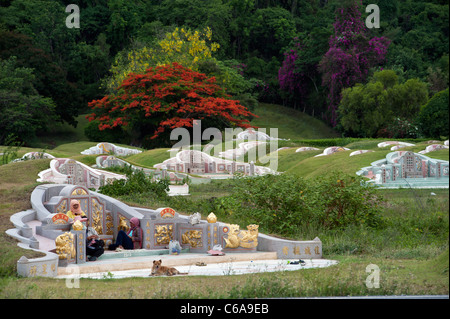 Un riposo della famiglia accanto a un tradizionale Cinese in stile grave al Thai-Chinese il cimitero di guerra di Kanchanaburi Thailandia Foto Stock