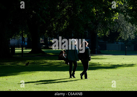 Due donne a piedi in London Fields Park, Hackney, Londra, Regno Unito Foto Stock