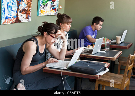 Due giovani donne e un uomo giovane concentrando sui loro schermi di computer nell'alcova del Bauhaus Libri & caffè internet cafe Seattle Foto Stock