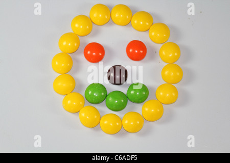 Multi-caramelle colorate disposte in forma di divertente faccia su sfondo bianco Foto Stock