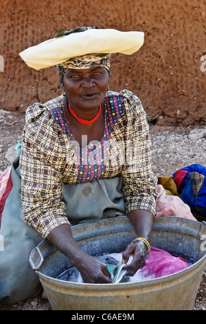 Herero donna lavando vestiti, Damaraland, Namibia Foto Stock