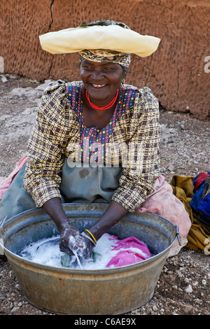 Herero donna lavando vestiti, Damaraland, Namibia Foto Stock