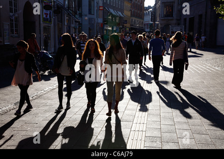 Ombre lunghe dal popolo in cammino sulla trafficata strada pedonale Strøget a Copenaghen retroilluminati da bassa serata estiva sun Foto Stock