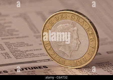 Regno Unito due pound coin in piedi sul bordo su uno sfondo di una pagina dal FT Foto Stock