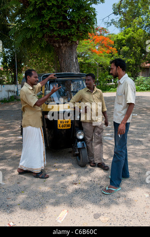 In rickshaw Drivers prendere rompersi vicino i cinesi reti da pesca a Fort Cochin, Kochi, India Foto Stock