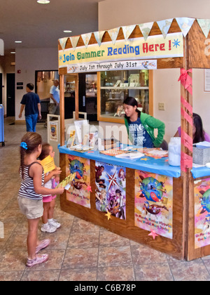 Asian volontari americani offerta estate consigli per la lettura di ispanici e i bambini asiatici in una biblioteca pubblica in Aliso Viejo, CA. Foto Stock