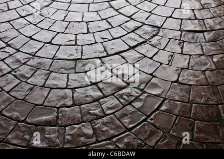 Rustico scuro pavimento di pietre per pavimentazione posati in una configurazione arrotondata Foto Stock