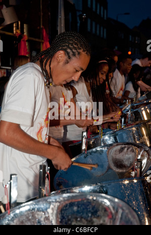 Membro della band da Rapso Orchestra di acciaio, tegame sul fuoco, giocando a tamburo di acciaio a Notting Hill Campionati del panorama Foto Stock