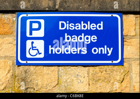 Badge disabili titolari solo segno su una parete in un parcheggio Foto Stock
