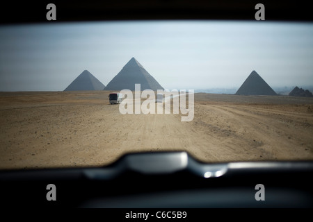 Gli autobus turistici attraversare il deserto vicino Kheops, Kephren e Micerino piramidi a Giza, vicino a Il Cairo, Egitto. Foto Stock