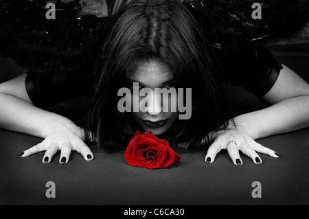 La donna in una immagine di un bel black angel con una rosa rossa in una mano Foto Stock