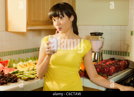 Razza mista donna frullato potabile in cucina Foto Stock